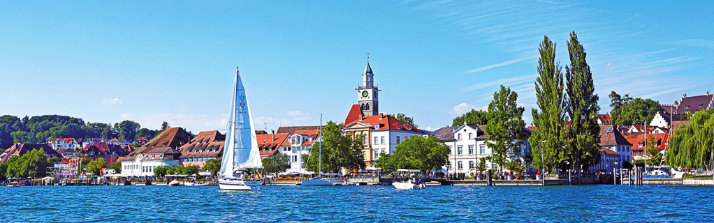 Blick vom Bodensee auf Überlingen mit Segelboot, Altstadt und Kirche St. Nikolaus bei Sommerwetter